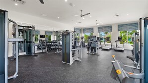 A gym with various exercise equipment, large windows, and a ceiling fan. - Last Minute Disney! Private Pool, Hot Tub & Themed Bedrooms. Book Now! #89755 (Orlando)