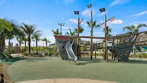 A playground with slides and climbing structures, surrounded by palm trees and a clear sky. - Last Minute Disney! Private Pool, Hot Tub & Themed Bedrooms. Book Now! #89755 (Orlando)