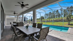 Un patio techado con piscina, mobiliario exterior y ventiladores de techo.