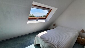 Een slaapkamer met dakraam, een bed, nachtkastje en een lamp.