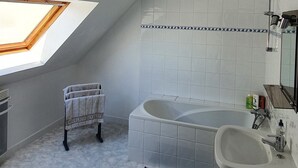 Een moderne badkamer met dakraam, een badkuip, een wastafel en een handdoekhouder.