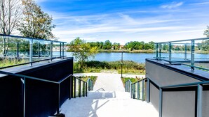 A modern outdoor staircase leading to a glass railing overlooking a lake. - Apartment with river view, sauna, and indoor pool (Dziwnow)