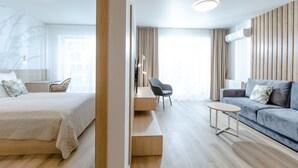 A modern hotel room with a bed, a sofa, a small table, and a chair. - Apartment with river view, sauna, and indoor pool (Dziwnow)