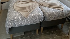 Un dormitorio con una cama grande, dos mesitas de noche, una ventana con cortinas y una obra de arte colgada en la pared.
