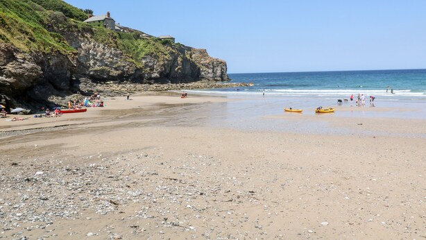 A beach with rocky cliffs, a clear sky, and kayaks on the sand. - Honeysuckle Cottage (St. Agnes)
