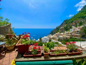 A terrace with potted plants and a view of a coastal village. - Casa Laura in Positano (Positano)