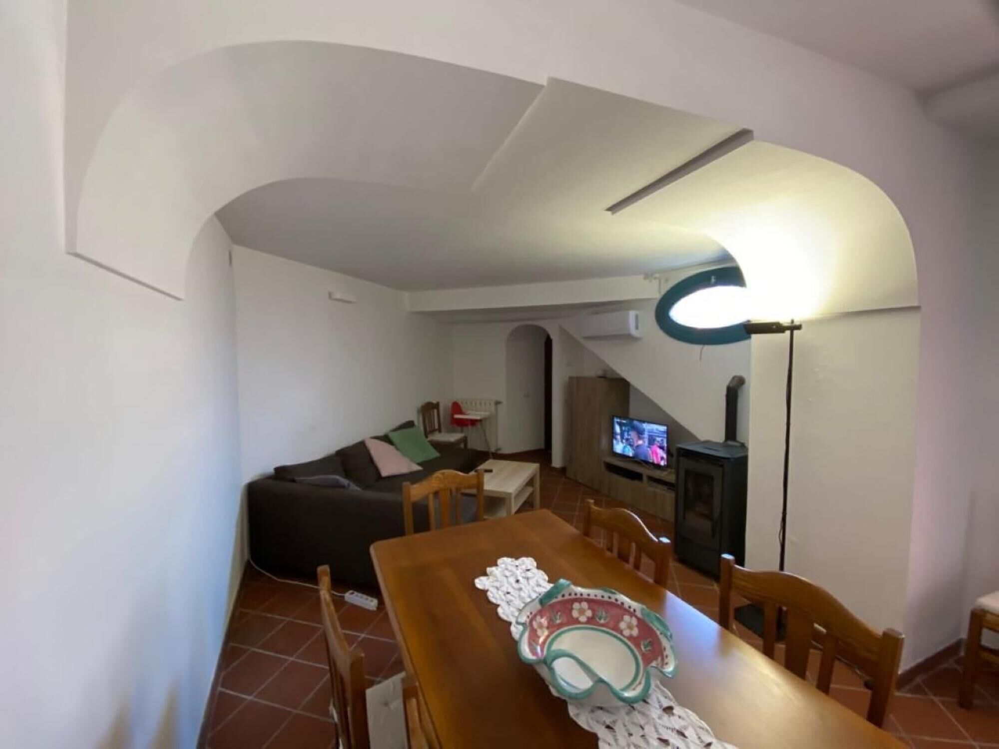 Una sala de estar acogedora con un sofá, una mesa de comedor con sillas, un televisor y una chimenea.