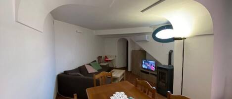 Una sala de estar acogedora con un sofá, una mesa de comedor con sillas, un televisor y una chimenea.
