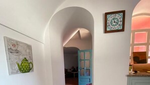 Ein Flur mit Heizkörper, einem weißen Stuhl und einer Tür zu einem anderen Raum.