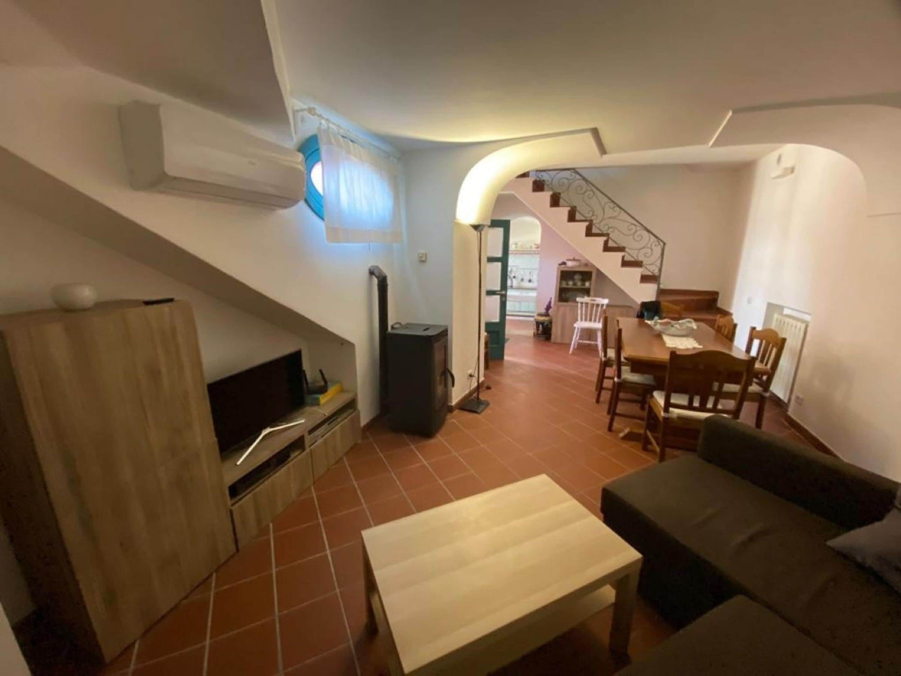 A living room with a TV, sofa, and dining area.