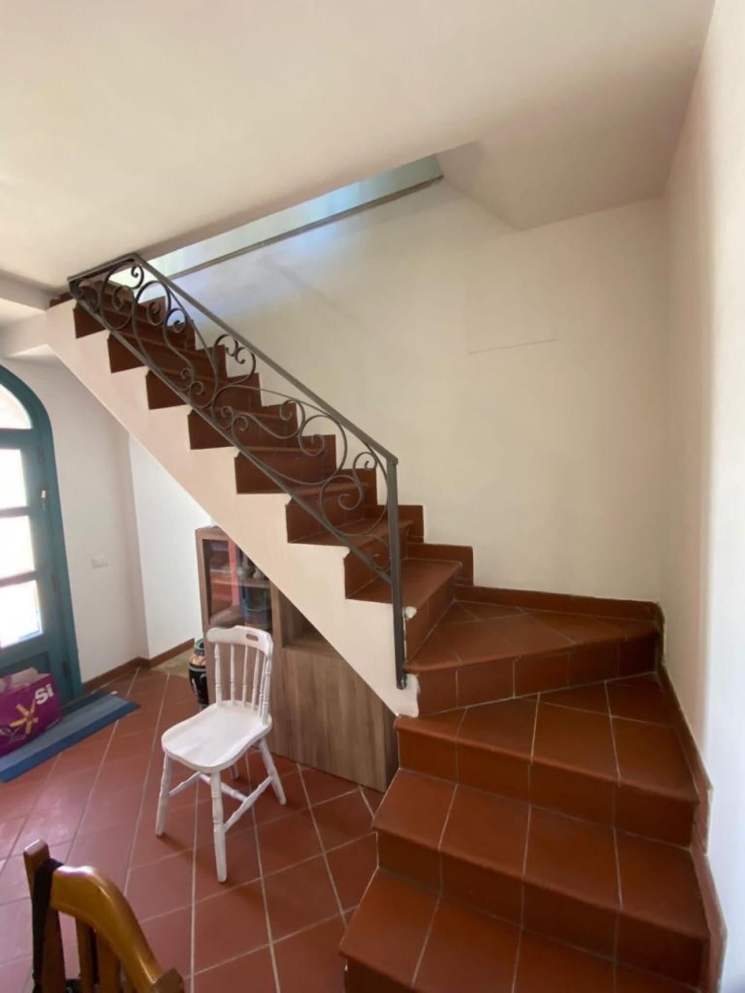Escada com azulejos marrons e guarda-corrimão de metal.