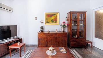 A living room with a wooden cabinet, a TV, a coffee table, and a painting on the wall.