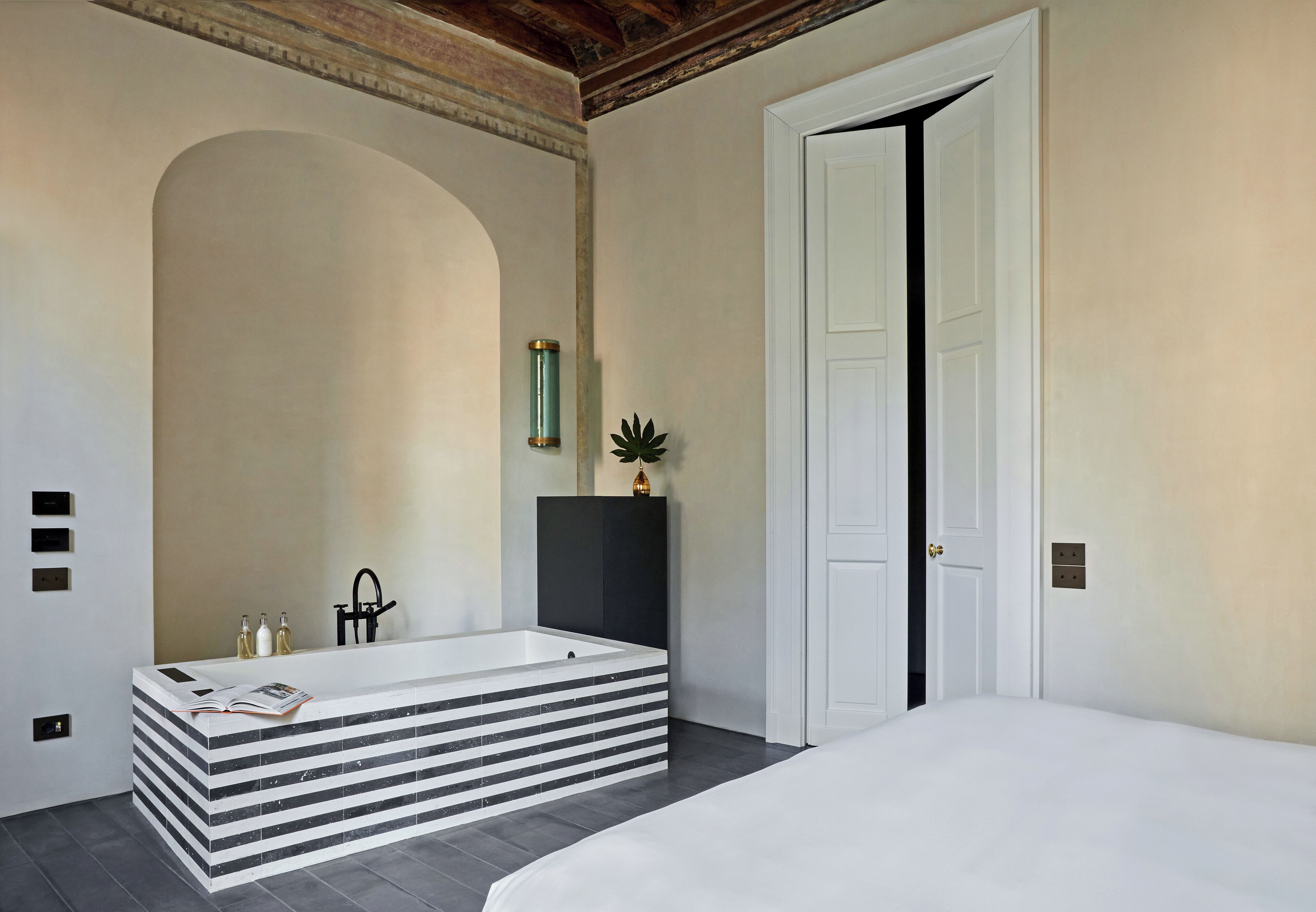 A modern bathroom with a freestanding bathtub, a large mirror, and a potted plant.