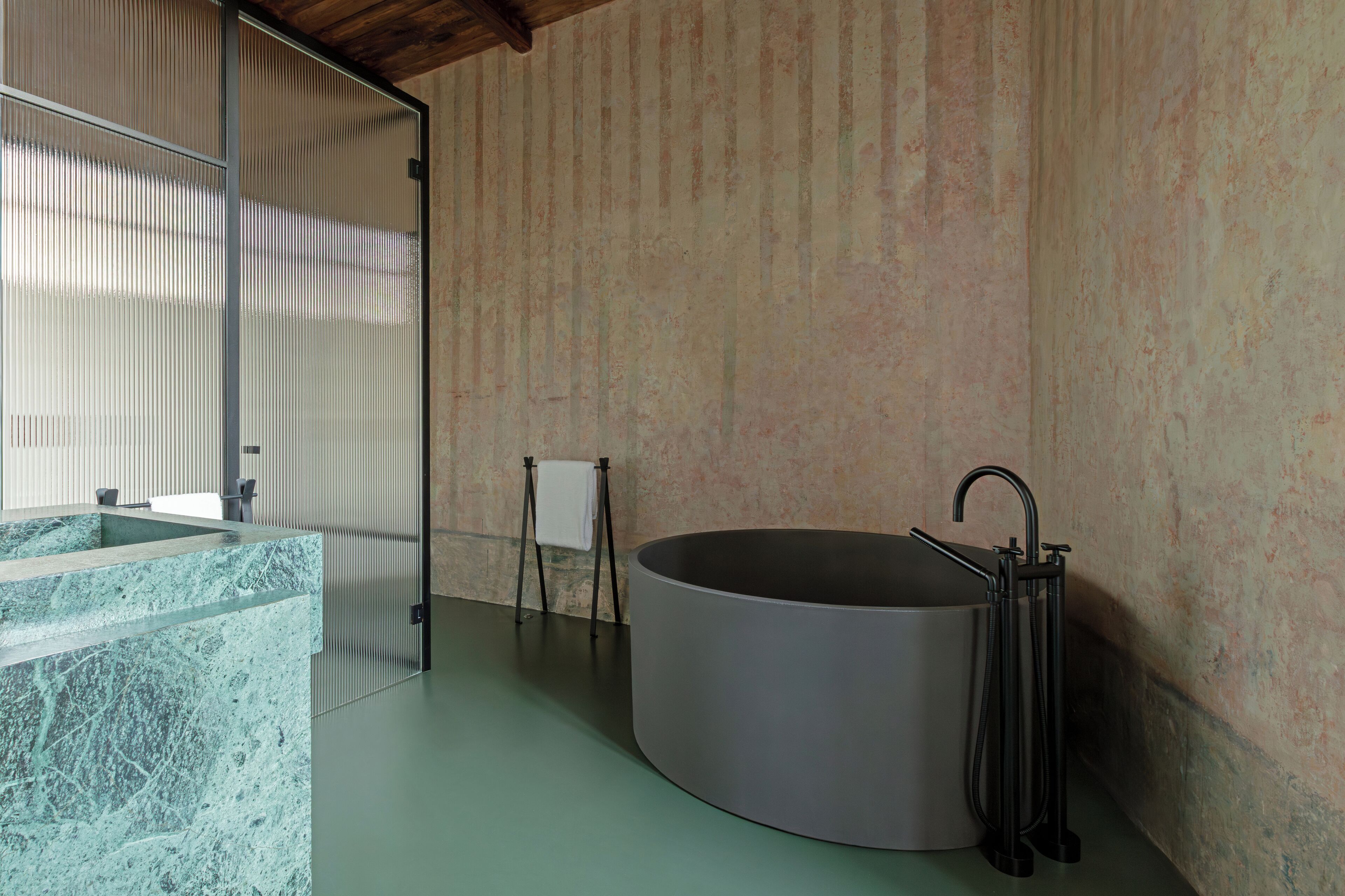 A modern bathroom with a freestanding bathtub, a marble sink, and a towel rack.