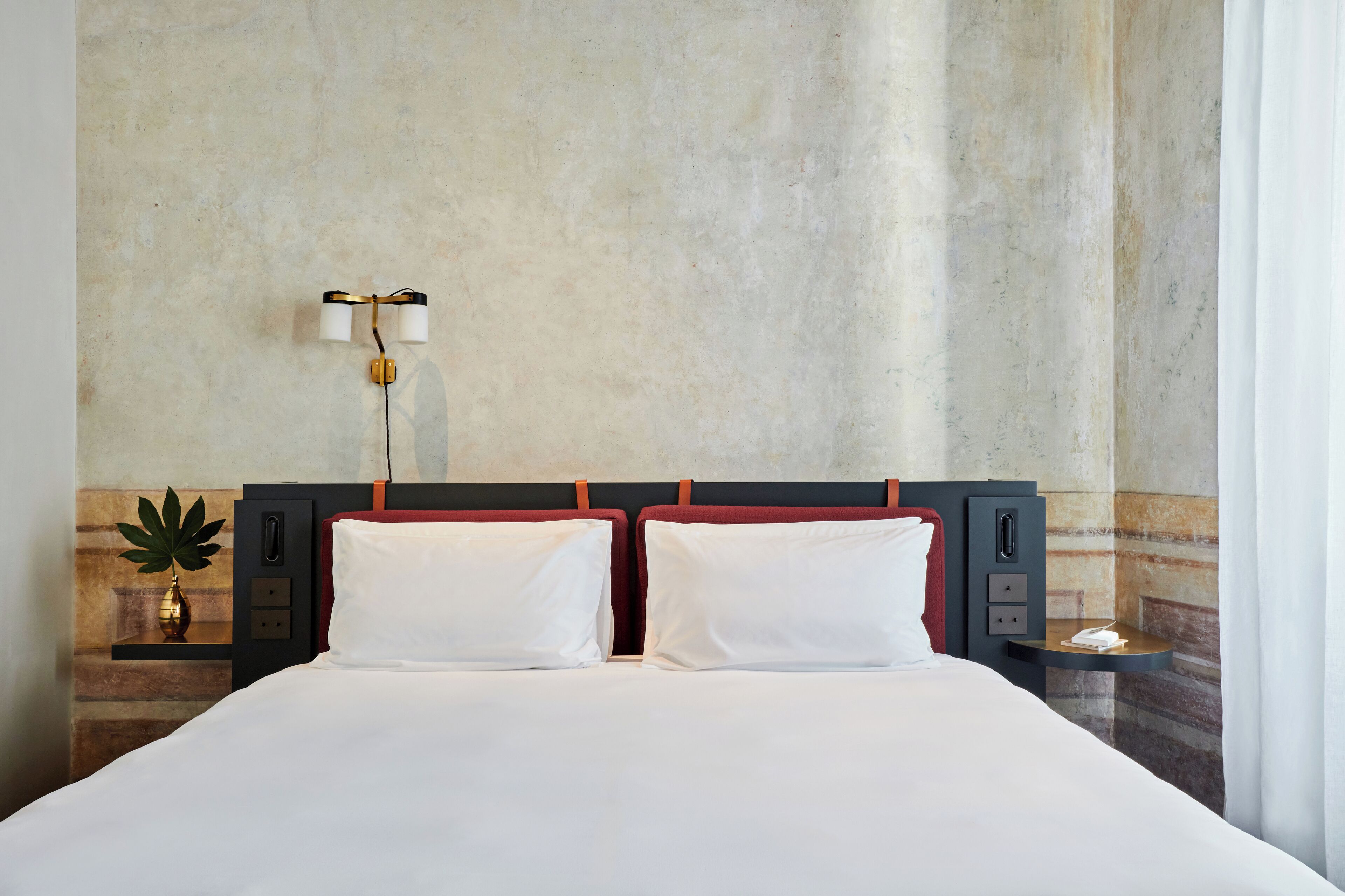 Ein Hotelzimmer mit einem großen Bett, zwei Nachttischen, einer Wandlampe und einer kleinen Pflanze.