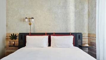 Ein Hotelzimmer mit einem großen Bett, zwei Nachttischen, einer Wandlampe und einer kleinen Pflanze.