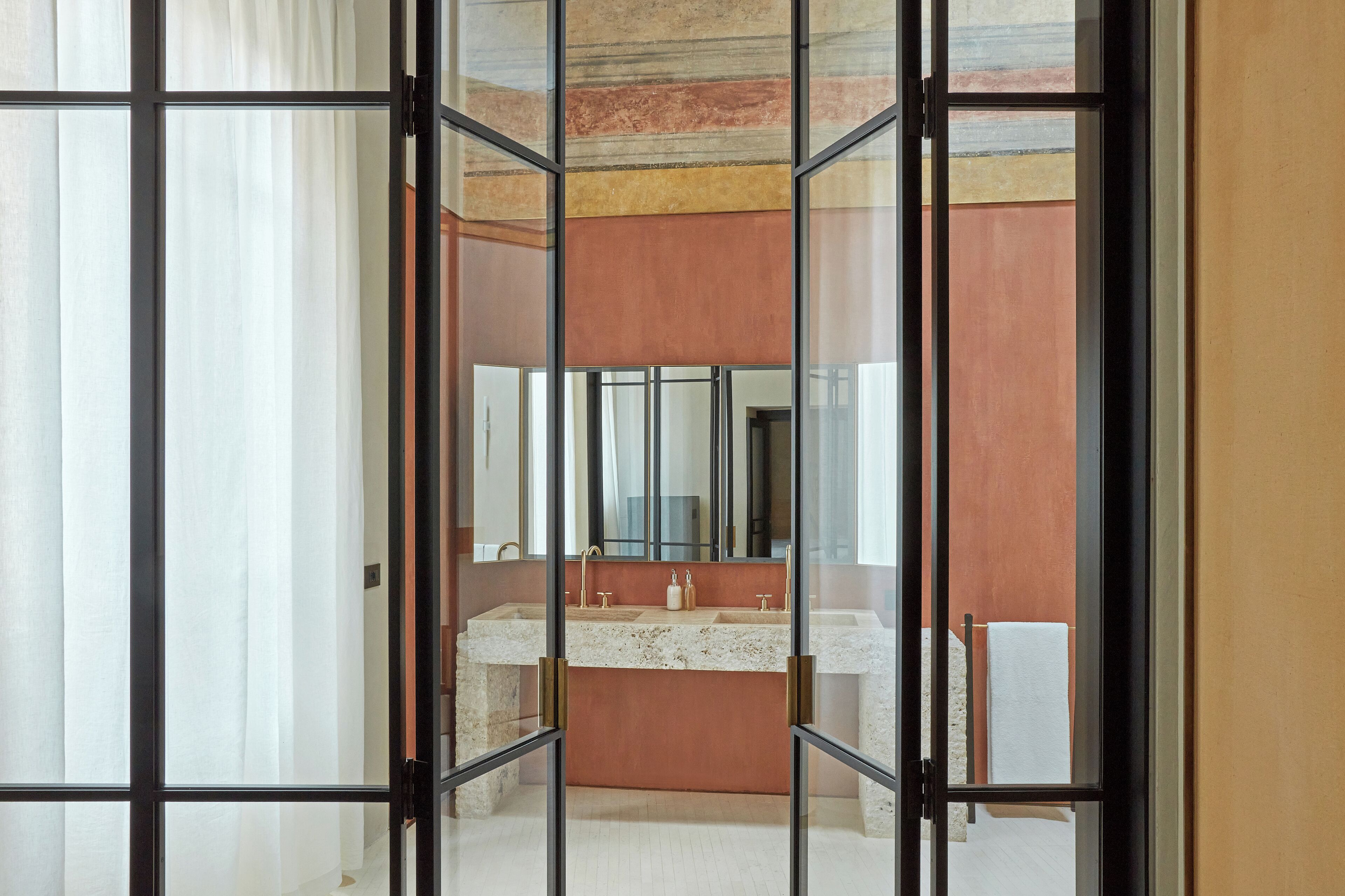 A bathroom with a large mirror, two sinks, and a towel rack.