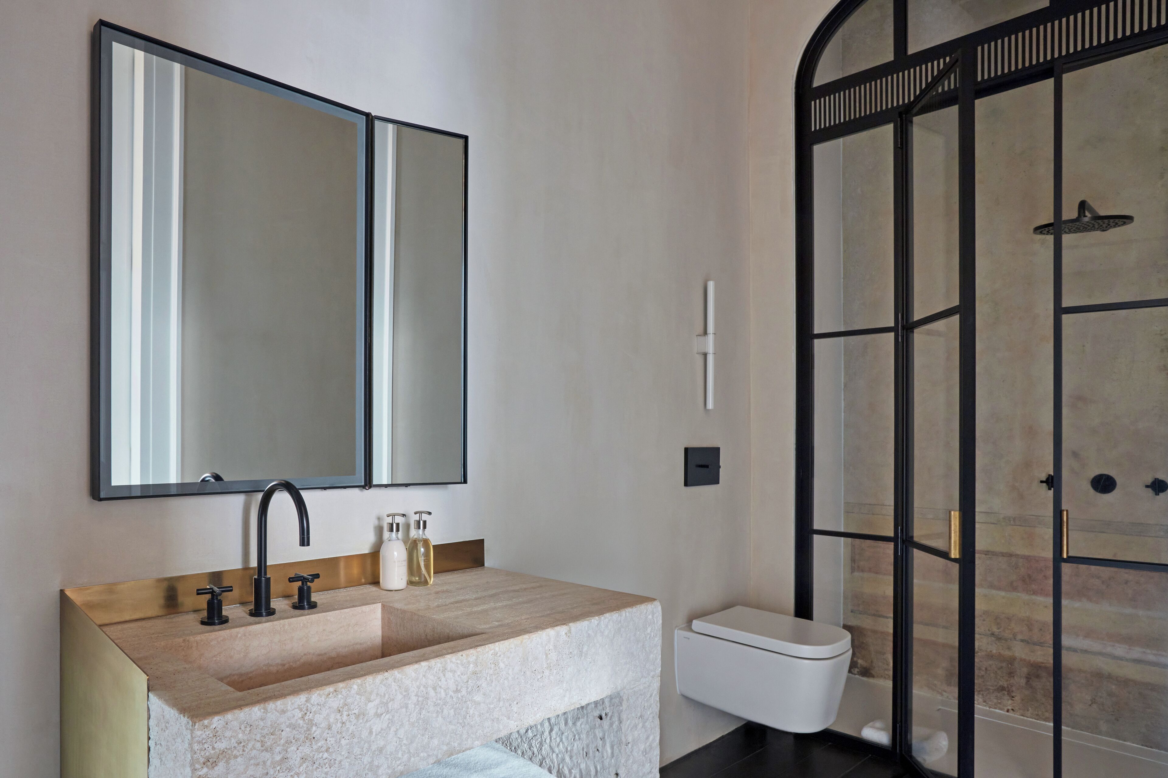 A modern bathroom with a large mirror, a beige sink, and a glass-enclosed shower.