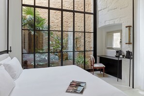 Un dormitorio con un ventanal grande, una cama, un escritorio y una silla.