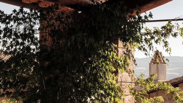 Un'area piscina con un muro in pietra e vista su una torre lontana.