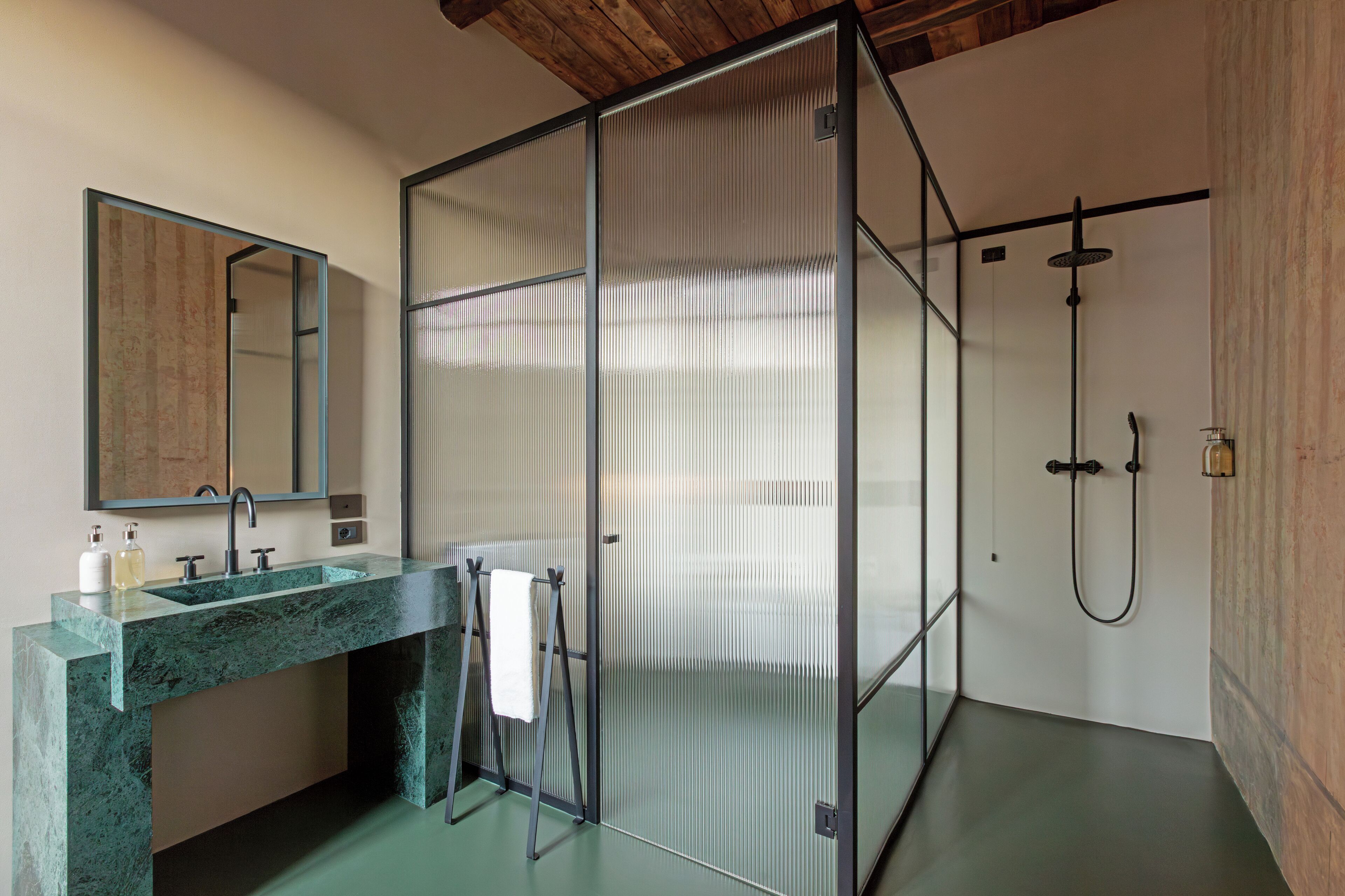 Un baño moderno con cabina de ducha de vidrio, lavamanos de mármol y un espejo grande.