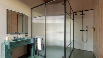 Un baño moderno con cabina de ducha de vidrio, lavamanos de mármol y un espejo grande.
