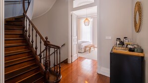 A wooden staircase leading to a bedroom with a bed and a small table.