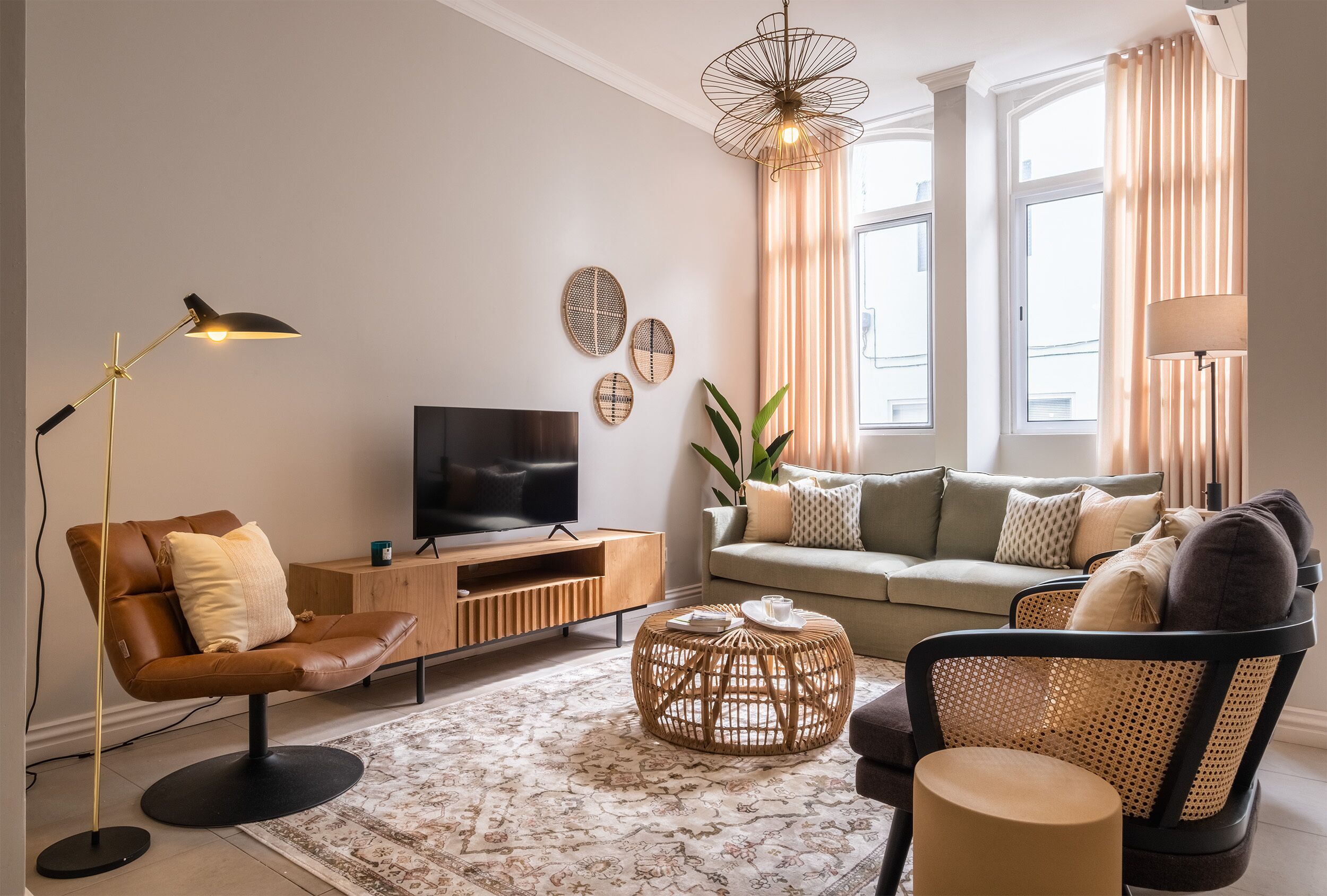 A modern living room with a sofa, armchair, TV, and decorative items.