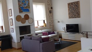 Un salon avec une cheminée, un canapé, un téléviseur et un mur en pierre.