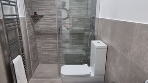 Un bagno moderno con doccia vetrata, un water e una vasca da bagno.