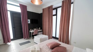 Una camera d'albergo con un letto, una scrivania, una sedia e una televisione.