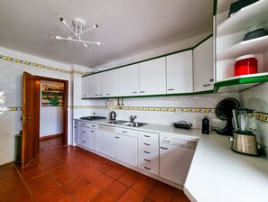 Une cuisine avec des meubles blancs, une cuisinière, un évier et un lave-vaisselle.