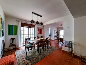 Ein geräumiger Essbereich mit großem Tisch und Stühlen, einem gemusterten Teppich und Blick auf das angrenzende Wohnzimmer.