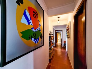 Un couloir avec une peinture abstraite aux couleurs vives sur le mur, une porte en bois et un sol carrelé.