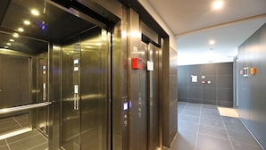 Ein moderner Aufzugsbereich mit Metallüren, Bedienfeldern und Notruftasten.