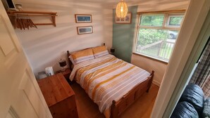 Un dormitorio pequeño y acogedor con una cama de madera, una mesita de noche, una lámpara y una ventana con persianas.
