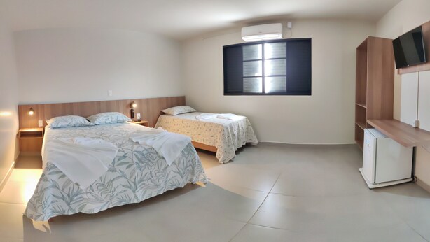 Une chambre avec deux lits, une télévision, une armoire et une fenêtre.