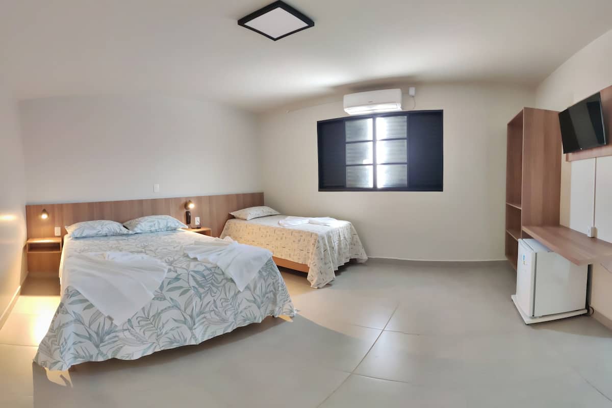 A bedroom with two beds, a TV, a wardrobe, and a window.