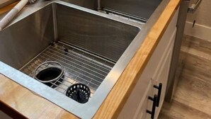 A kitchen with a stainless steel sink, wooden countertop, and a window with blinds. - New! Renovated 2BD Home in Downtown (Billings)