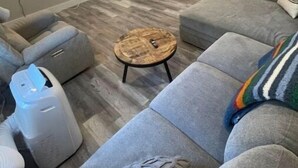 A modern living room with a grey sofa, a round coffee table, and a ceiling fan. - New! Renovated 2BD Home in Downtown (Billings)
