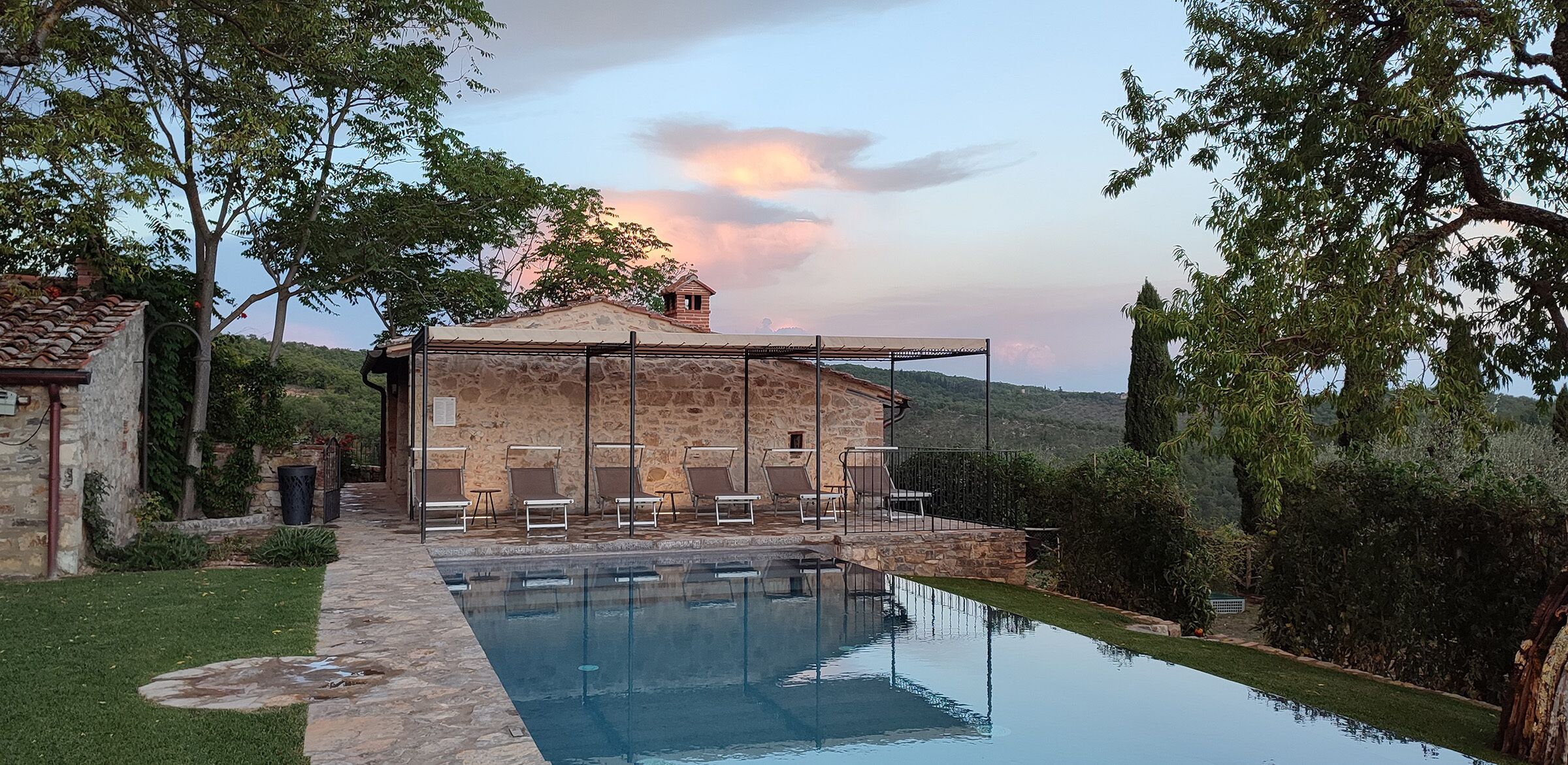 A stone building with a pool and lounge chairs.