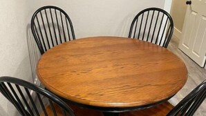 Een ronde houten tafel met vier zwarte metalen stoelen.