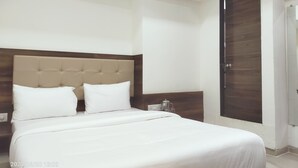 Hotellihuone, jossa on suuri sänky, puinen pääty, yöpöytä ja vaatekaappi.