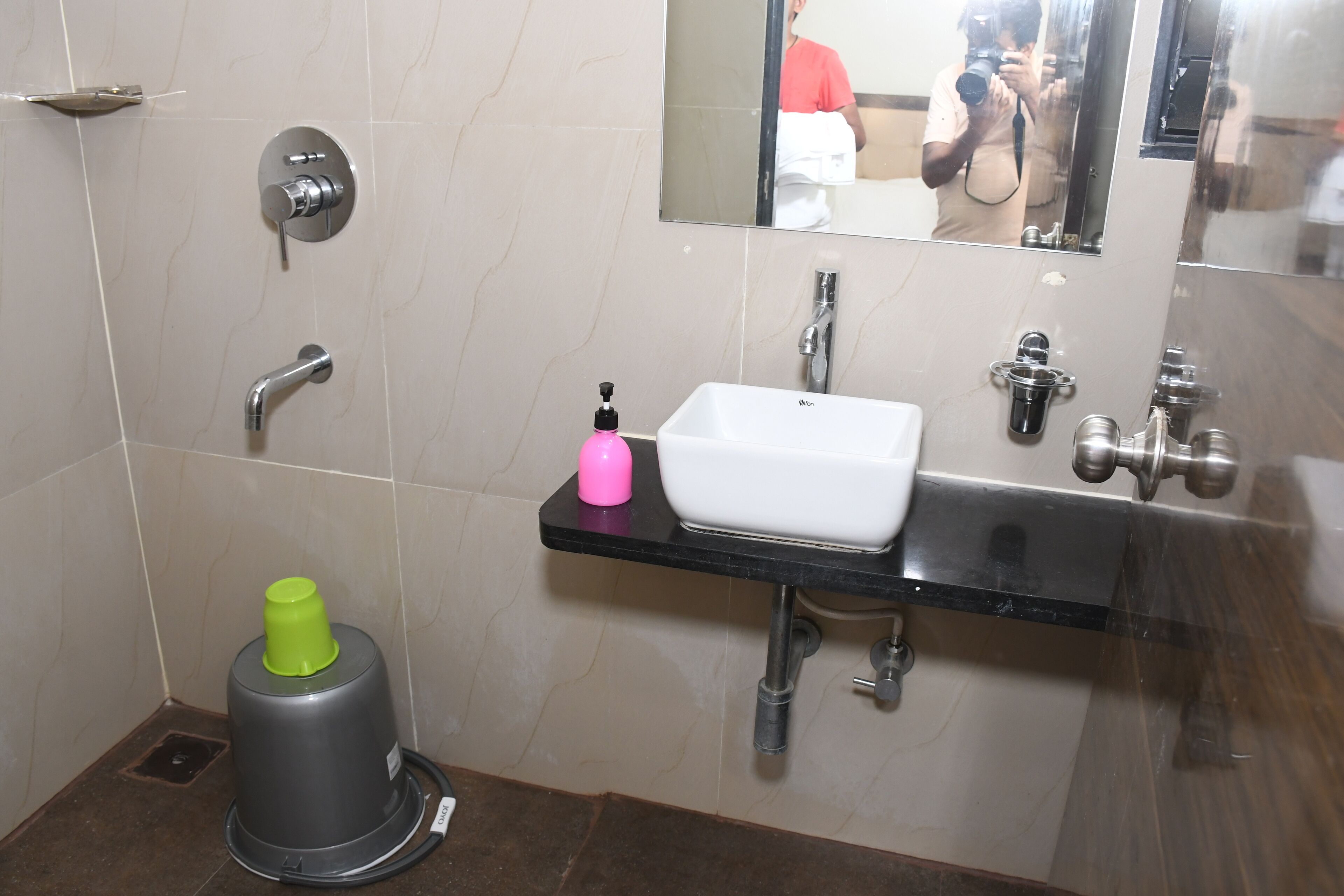 A modern bathroom with a white sink, a mirror, and a shower area.