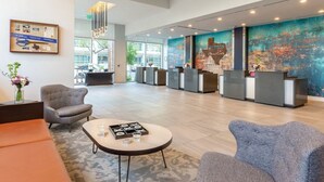 A spacious lobby with a reception desk, seating area, and a large abstract mural on the wall. - 2BD/Austin - Full Kitchen, W/D, Balcony, Fire Pit! (Austin)