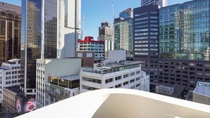 Een modern stadsbeeld met hoogbouw, waaronder een opvallend glazen wolkenkrabber en een gebouw met een rood dak.