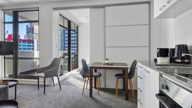 Een moderne keuken met een eethoek, grote ramen en uitzicht over de stad.