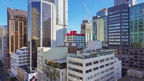 Een stadsbeeld met moderne wolkenkrabbers, waaronder een opvallend glazen kantoorgebouw en een gebouw in aanbouw.