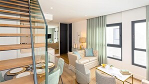 A modern living room with a staircase, a sofa set, a dining table, and large windows. - Genteel Home Betis XXVI (Seville)