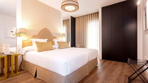 Een moderne hotelkamer met een groot bed, een nachtkastje met een lamp, een garderobe en een kledingrek.